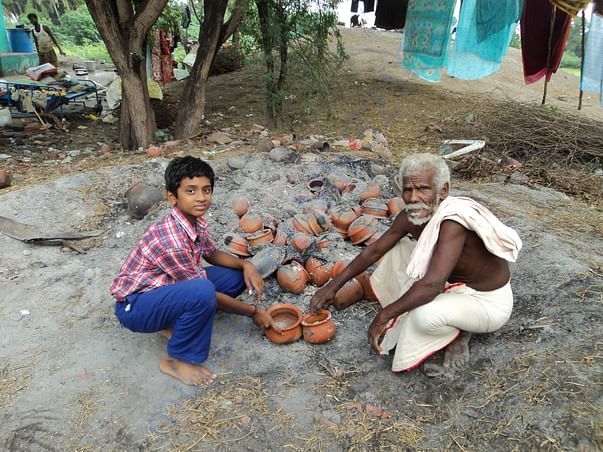 Student assisting his grandfather in pottery