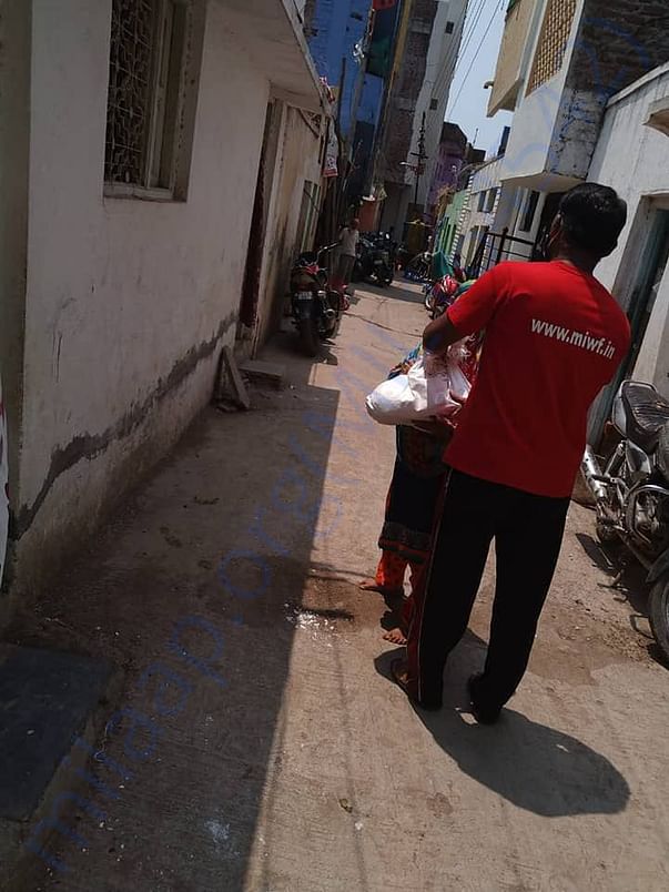 A poor lady being handed Ration kit by MIWF volunteer