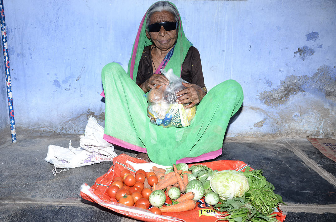 Poor oldagewoman getting monthly food provisions from best charity
